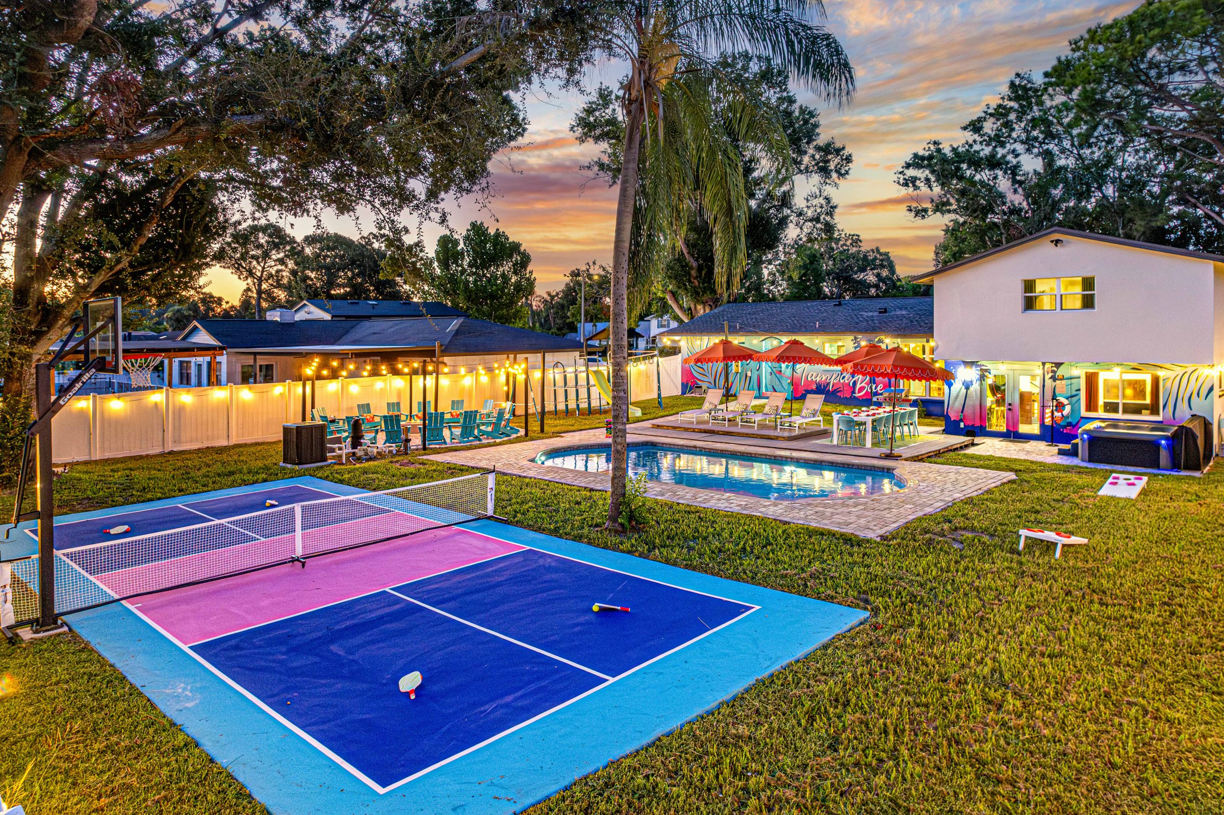 The pickleball court at dusk with the string lights coming on over the pool