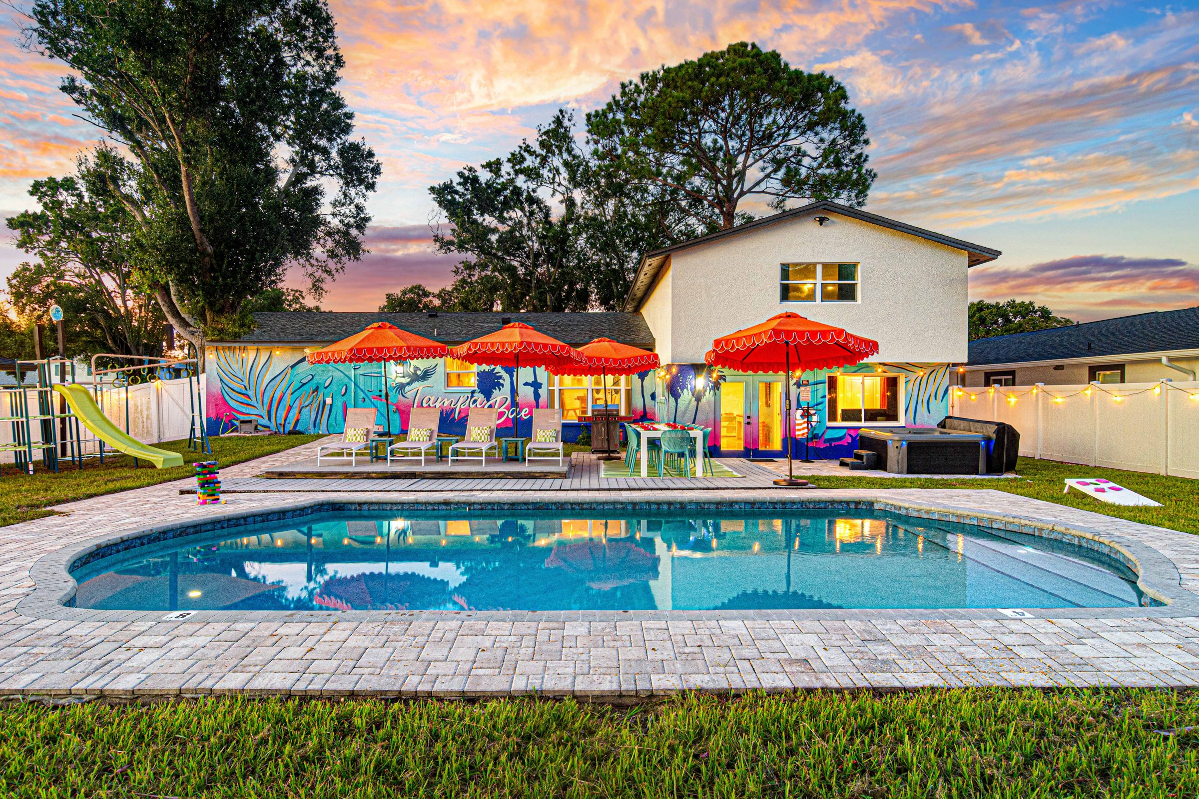 Twilight at Tampa Bae: the pool glowing, umbrellas up, the mural lit, and the whole house waiting for your crew
